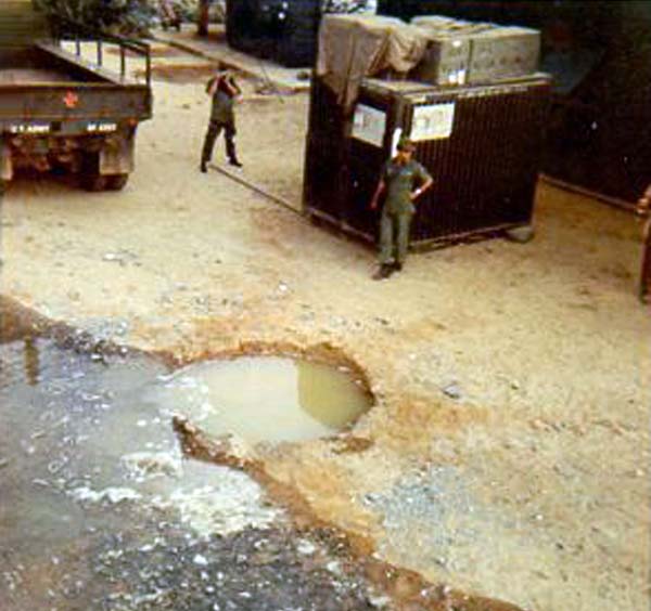 14. Da Nang AB: 366th TFW: Rocket crater at Gunfighter Village and outside my barracks back door. Unrelated to the bomb dump explosions. [Peter Halferty photo].